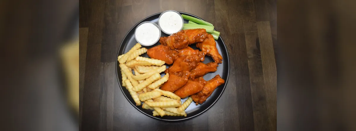 Buffalo wings, crinkle fries and dipping sauces on a plate